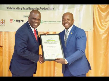 Norman Grant (left), coffee taster receives Agricultural Legacy Award from Pearnel Charles Jr, minister of agriculture and fisheries.