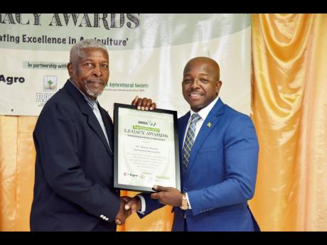Agronomist/ researcher, Thomas Burton (left), receives Agricultural Legacy Award from Pearnel Charles Jr, minister of agriculture and fisheries.