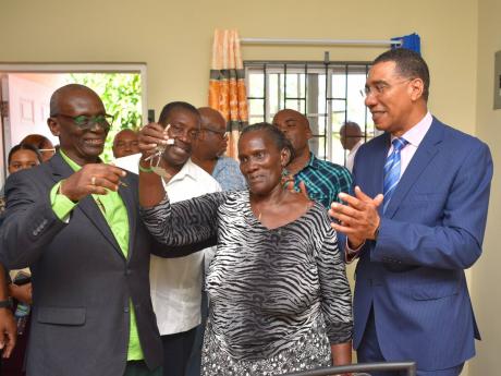 Norma ‘Peaches’ Folkes shows off the keys to her new home as she is cheered on by Minister of Local Government Desmond McKenzie (left), St Mary Western Member of Parliament Robert Montague (second left) and Prime Minister Andrew Holness (right).