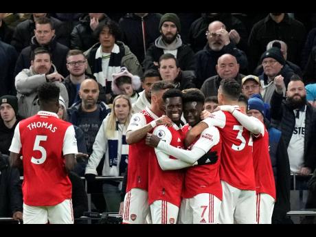 Arsenal players celebrate after scoring during the English Premier League match between Tottenham Hotspur and Arsenal at the Tottenham Hotspur Stadium in London, England yesterday.