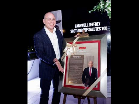 Outgoing chair of Scotia Group Jamaica, Jeffrey Hall, pauses for a photo with the citation he received at his farewell party.