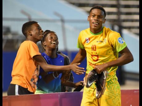 Kingston College’s Dujuan Richards is greeted by fans on the sidelines after he was substituted in an All-Manning versus All- daCosta Cup football match at the National Stadium on Saturday. Richards scored one of two goals for the All-Manning team in the