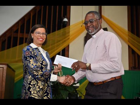 Allison Peart, president of the Institute of Chartered Accountants of Jamaica (ICAJ), presents the institute’s donation towards outreach programmes at Webster Memorial United Church to the Reverend Delroy Harris during a thanksgiving service held on Sund