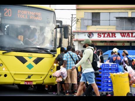 Commuters jostle for space as they prepare to board a Jamaica Urban Transit Company bus at the South Parade terminus in downtown Kingston on Wednesday. 