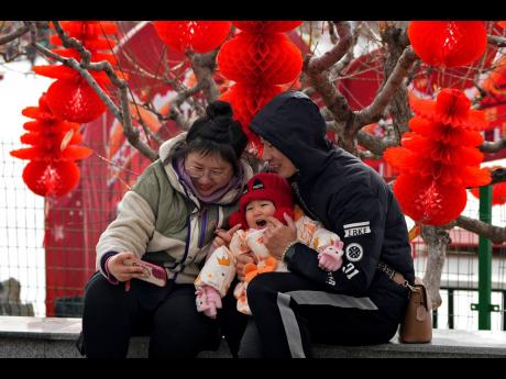 A couple take a selfie with their toddler in front of Lunar New Year decorations at a public park in Beijing.