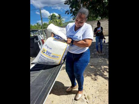 Sydonnie Gyles, president  of the Kiwanis Club of Young Professionals lifts a bag of Nutramix feed at the Single Mothers Programme presentation in St Catherine on Sunday, January 22.