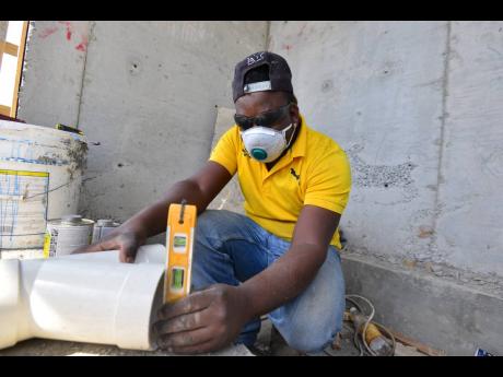 Plumber Andre Smith takes a measurement at a construction site in Silverstone, Portmore. Urging a rethink of technical and vocational education and training, HEART/NSTA Trust Managing Director Taneisha Ingleton says “we can use skills to leverage and gen
