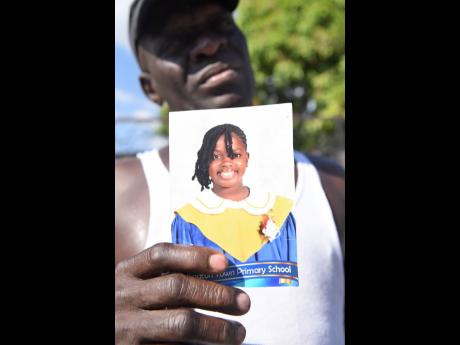 Anthony Hugh holds a picture of his 12-year-old daughter, Liah Hugh. The Kingston High School student perished in a fire that destroyed her home on Giltress Street in Rollington 
Town, Kingston, on Thursday.