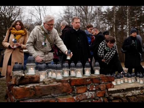 People place candles at the former crematorium as they attend a ceremony in the former Nazi German concentration and extermination camp Auschwitz during ceremonies marking the 78th anniversary of the liberation of the camp in Brzezinka, Poland yesterday.