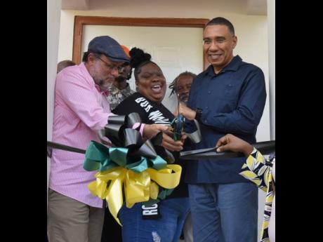 Thia Jones (centre) could not hide the joy she felt while cutting the ribbon to her new house in Hopeful Village, St Andrew, with Prime Minister Andrew Holness (right) and St Andrew Southern Member of Parliament Mark Golding. Jones was given the keys to th