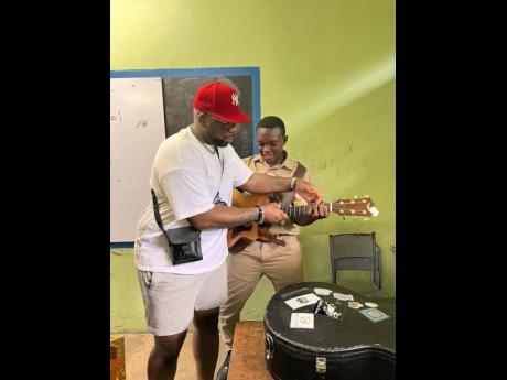 Jelani Aswad (left) shows a student of Waterford High School how to play the guitar, during a recent tour of the institution.