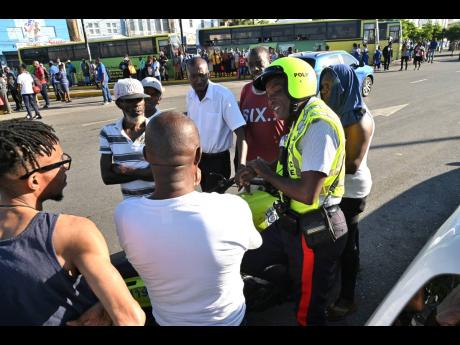 A policeman talking to taxi operators who went on strike last November for the implementation of a traffic amnesty at North Parade in downtown Kingston.