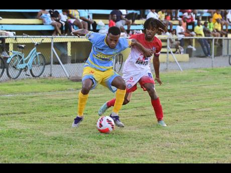 Orlando Brown (left) of Waterhouse FC shields the ball from Portmore United’s Alex Marshall during their Jamaica Premier League match at the Waterhouse mini stadium yesterday. The game ended in a 1-1 draw. 