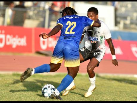  Jevaughn Brown (left) of Molynes United is tackled by Cavalier's Brian Elshot during their Jamaica Premier League match at the Ashenheim Stadium, Jamaica College yesterday.  Cavalier won 2-0.