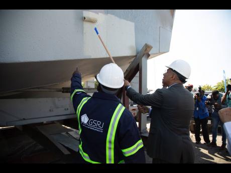 Prime Minister Andrew Holness paints the hull of a docked vessel at the launch of the German Ship Repair Jamaica shipyard project last week.