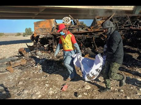 Rescue workers collect remains from the burnt wreckage of a bus accident in Bela, an area of Lasbela district of Balochistan province, Pakistan on Sunday.