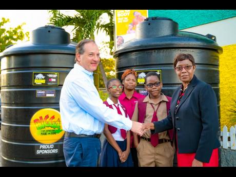 Wisynco’s Director of Marketing, Francois Chalifour (left), and Half Way Tree Primary School principal Carol O’Connor Clarke shake hands during the presentation of two 1,000-gallon water storage tanks to the institution on January 19. Looking on are th