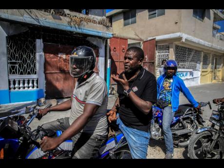 Jimmy Cherizier, the leader of the ‘G9 Family and Allies’ gang, talks with members of his gang while taking a ride on the back of a motorcycle in his district of Delmas 6 in Port-au-Prince, Haiti, yesterday.