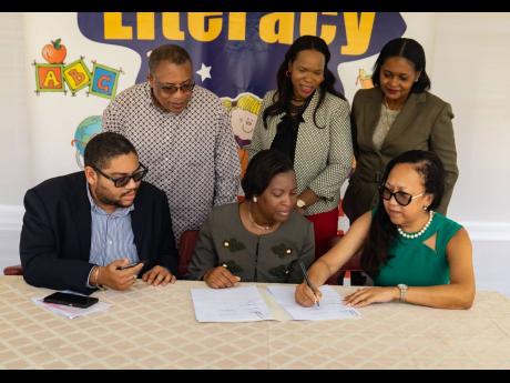 Director of the D&G Foundation Dianne Ashton-Smith (seated right) and principal of the Seaview Gardens Primary School, Sangieanna Reid-Prince (front centre), sign an MOU to facilitate the school’s literacy intervention programme. Also present at the sign