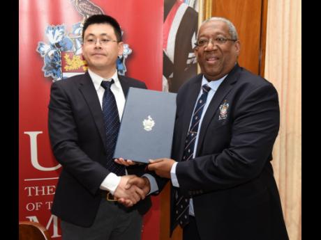 Dangran Bi (left), country manager of China Harbour Engineering Company Limited (CHEC), and Professor Dale Webber, pro vice-chancellor and principal of The University of the West Indies (UWI), Mona, pose for a photo after signing a cooperation agreement at