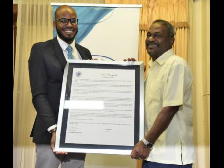 Jovan Johnson (left), treasurer of the Press Association of Jamaica, presents a citation to Keith Campbell, veteran cameraman and technical director, and production manager.
