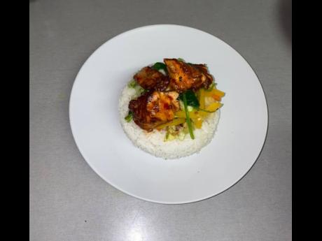 The barbecued salmon is served in a bed of white rice.