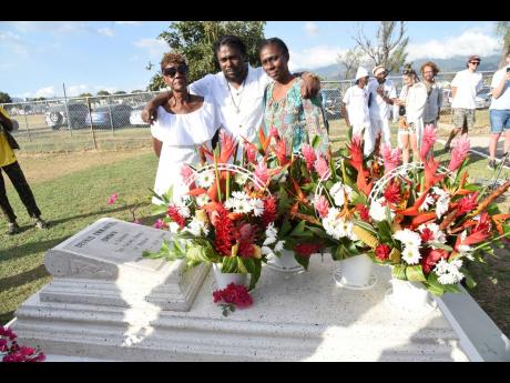From left: Mary Brown, Franklyn Brown, and Michelle Brown, siblings of Dennis Brown, lay wreaths on his grave at the National Heroes Park on his birthday, February 1.