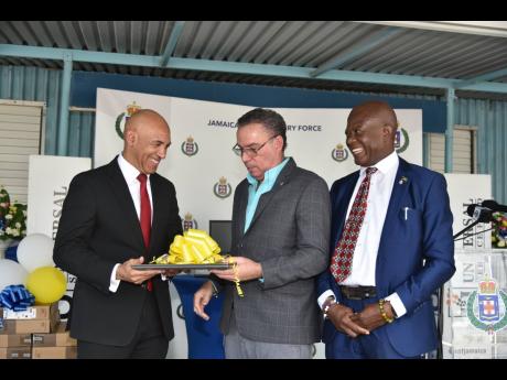 Commissioner of Police Major General Antony Anderson (left) grins while receiving one of 61 computers from Minister of Science, Energy and Technology Daryl Vaz (centre) and CEO of the Universal Service Fund, Daniel Dawes, during a handover ceremony at Harm