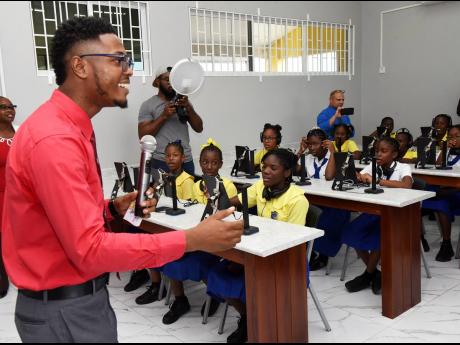Kerome Woolery (left) senior teacher at Old Harbour Primary school, conducts a class in the new ICT room shortly after the hand over ceremony on Thursday.