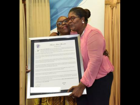 Maxine Shrouder (right), librarian at the Jamaica Information Service for 35 years, gets a hug and kiss from Christine King after receiving her citation.
