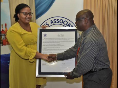 Kimberley Hibbert (left), secretary of the Press Association of Jamaica, awards Ian Watkis, press technician at the Jamaica Observer for 27 years.