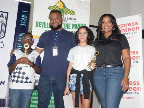 Champion boy and girl at the Mona Preparatory School PTA Chess Tournament, Mona Prep’s Khaleel Johnson-Bartlett (left) and Kayla Moses (second right), of Creative Arts Learning Centre, display  their first-place trophies alongside sponsorship representat