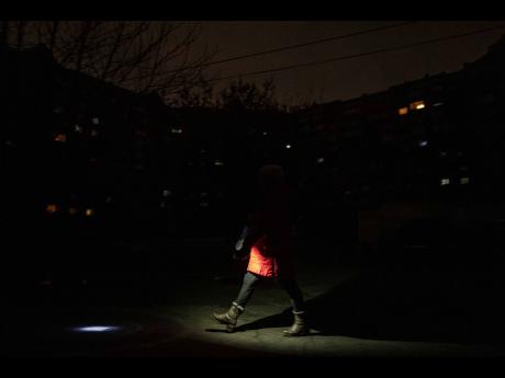 A woman lights up the road with a flashlight during blackout in Kyiv, Ukraine, yesterday.