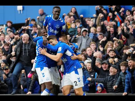 Everton's James Tarkowski (centre) celebrates with teammates after scoring their opening goal during the English Premier League football match against Arsenal at Goodison Park in Liverpool, England today. It was the only goal of the match.