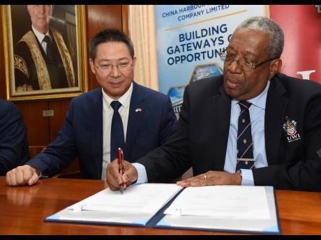 Chen Daojiang (left), ambassador of the People’s Republic of China to Jamaica, looks on as Professor Dale Webber, pro- vice-chancellor and principal, The University of the West Indies (UWI), Mona campus, signs a cooperation agreement for a material testi