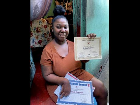 Sudan Lawson shows off some of the certificates she was awarded while attending Mona High School. The disabled young woman has been unable to secure a job since graduating with five subjects nearly four years ago.