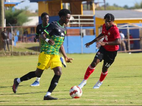 Jamaica’s Dyllan John dribbles away from the attentions of Trinidad & Tobago’s Malachi Webb during their under-17 international friendly at the STETHS Sports Complex yesterday.