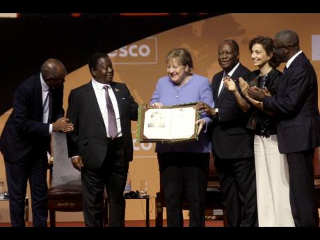 Former German Chancellor Angela Merkel (centre) receives the Felix Houphouet Boigny prize in Yamoussoukro, Ivory Coast, yesterday. Merkel has been honoured with the UNESCO peace prize for her efforts to allow more than 1.2 million migrants into Germany bet