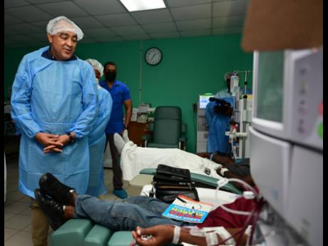 Health and Wellness Minister Dr Christopher Tufton (left) interacts with a patient undergoing dialysis during a tour of the Kelly Hoo Haemodialysis Unit at the Spanish Town Hospital in St Catherine on Wednesday.