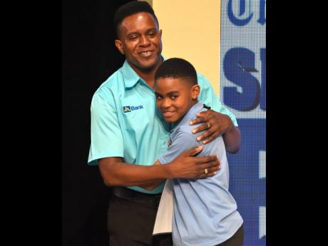 Taevion Morgan gets a hug from coach Errol Campbell shortly after tasting victory in The Gleaner’s Children’s Own’s Spelling Bee Championship on Wednesday.