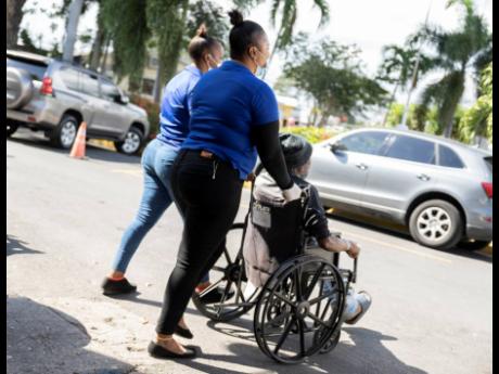 Two female workers are seen on the Spanish Town Hospital compound on Wednesday. CAPRI, in its report titled 'Fair Pay', is pushing for transparency in salary scales to bridge the gender gap.