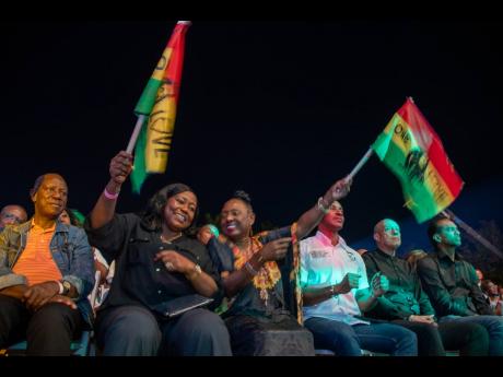 Minister of Tourism and Cultural Affairs in Sierra Leone, Dr Memunatu B Pratt, (left) and Minister of Culture, Olivia Grange, are all smiles as they wave their One Love flags at the Bob M rley Day concert hosted by Minister Grange at Emancipation Park last