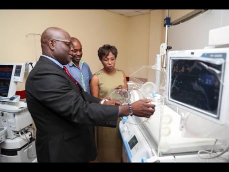 Philbert Perry (left), assistant vice president, Sagicor Life, learns about the uses of an incubator from Dr Jacqueline Wright-James, senior medical officer at Spanish Town Hospital, while technical director at Medical Link, Lainsworth Walker (centre) look