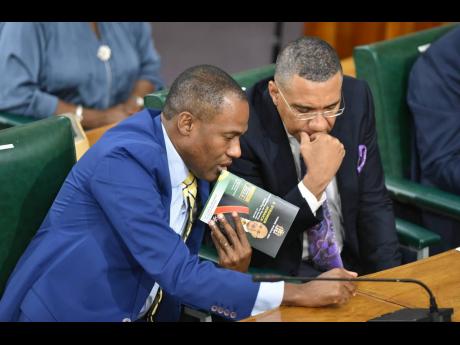 Finance Minister Dr Nigel Clarke (left) and Prime Minister Andrew Holness in a tête-à-tête in Parliament Tuesday. 