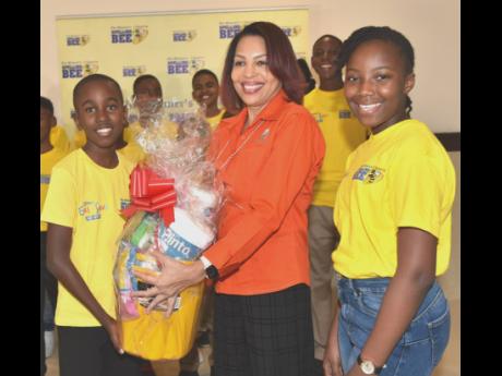 Marketing Manager of Manpower & Maintenance Services Ltd Group (MMS) Sandra Letts presents a gift package to Clarendon’s Spelling Bee champion, Mickran Campbell, while Hanover’s representative Romecia Spense (right) as well as other parish finalists sh
