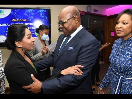 Edmund Bartlett, Jamaica’s minister of tourism, greets Aradhana Khowala, founder and CEO of Aptamind Partners, during the opening ceremony of the Global Tourism Resilience Conference at the Regional Headquarters of The University of the West Indies, Mona