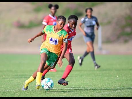 Excelsior High School’s Shaneil Buckley (left) dribbles by Bridgeport High School’s Maria Heslop in the teams’ ISSA Tip Friendly Society School Girls’ Competition opener at the Stadium East Sports Complex yesterday.