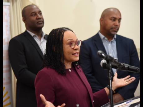 Senator Donna Scott-Mottley addresses a press conference at the Office of the Leader of the Opposition on Thursday. Looking on are People’s National Party General Secretary Dr Dayton Campbell (left) and Julian Robinson, opposition spokesman on finance.