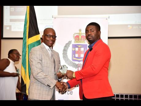 Assistant Commissioner of Police Clifford Chambers (left) presents a plaque to Detective Corporal Dwayne Gibbs of St James for his outstanding contribution to the Jamaica Constabulary Force.