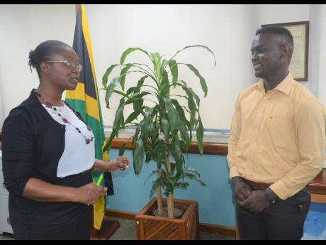 Business and Entrepreneurship Development Manager at the Jamaica 4-H Clubs, Villet Kelly-Bennett speaking with cattle farmer of Colley Mountain, Manchester, Okeito Thompson, who was the recipient of the Prime Minister’s Youth Award for Agriculture in 202